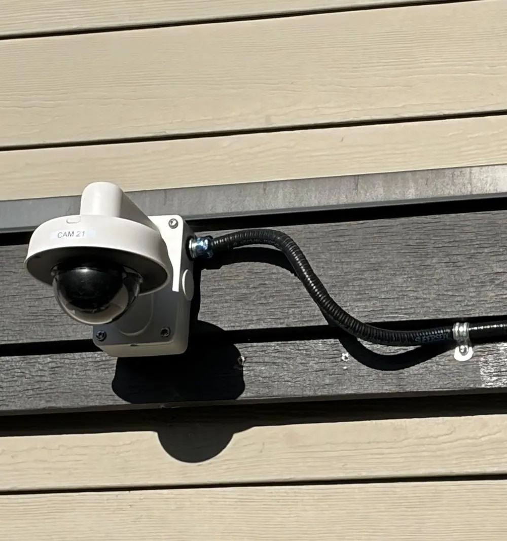 Outdoor dome camera with flexible conduit on siding