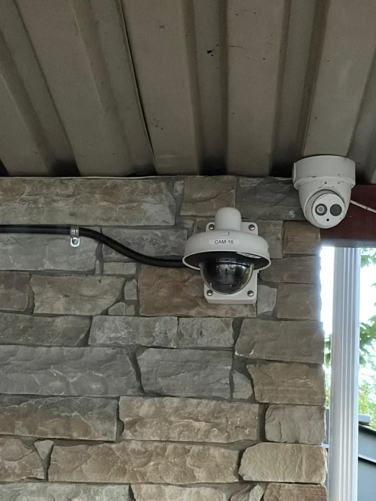 New dome camera beside an older turret camera on a stone wall