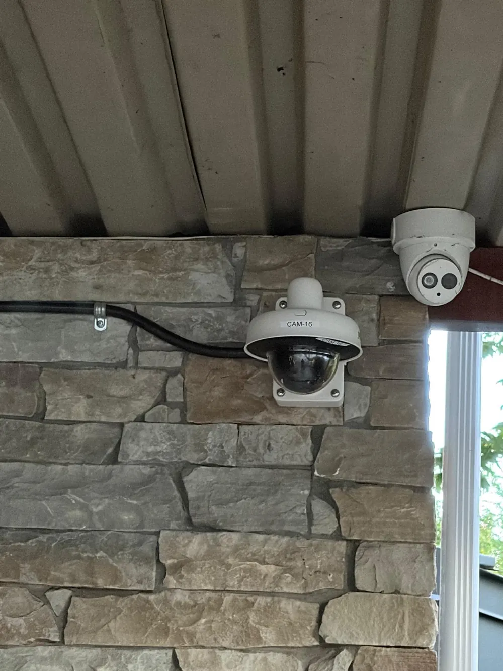 New dome camera beside an older turret camera on a stone wall