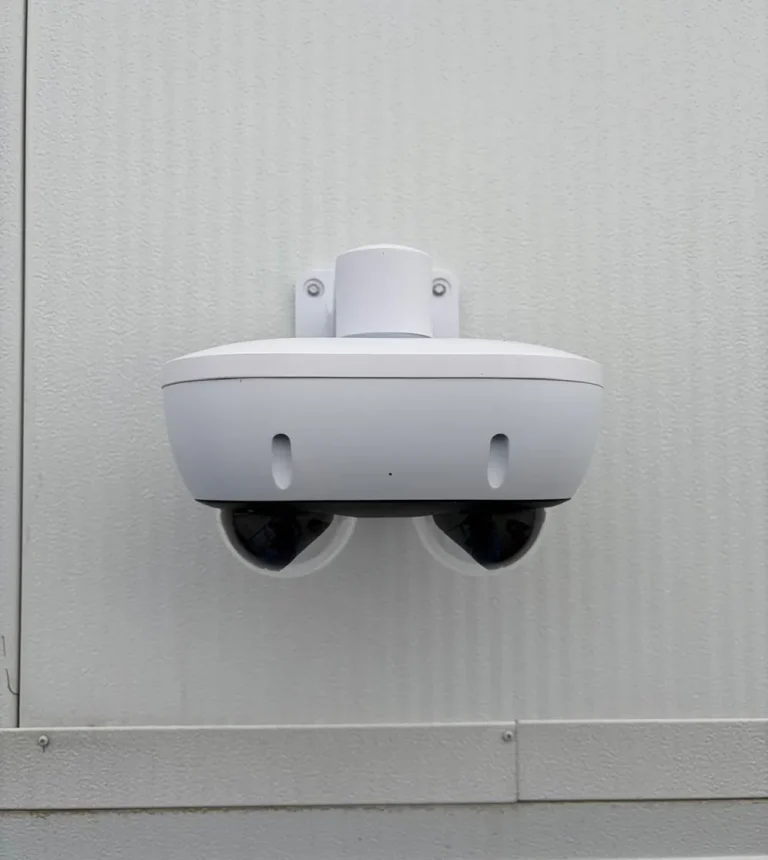 Dual-lens exterior camera mounted on a white wall