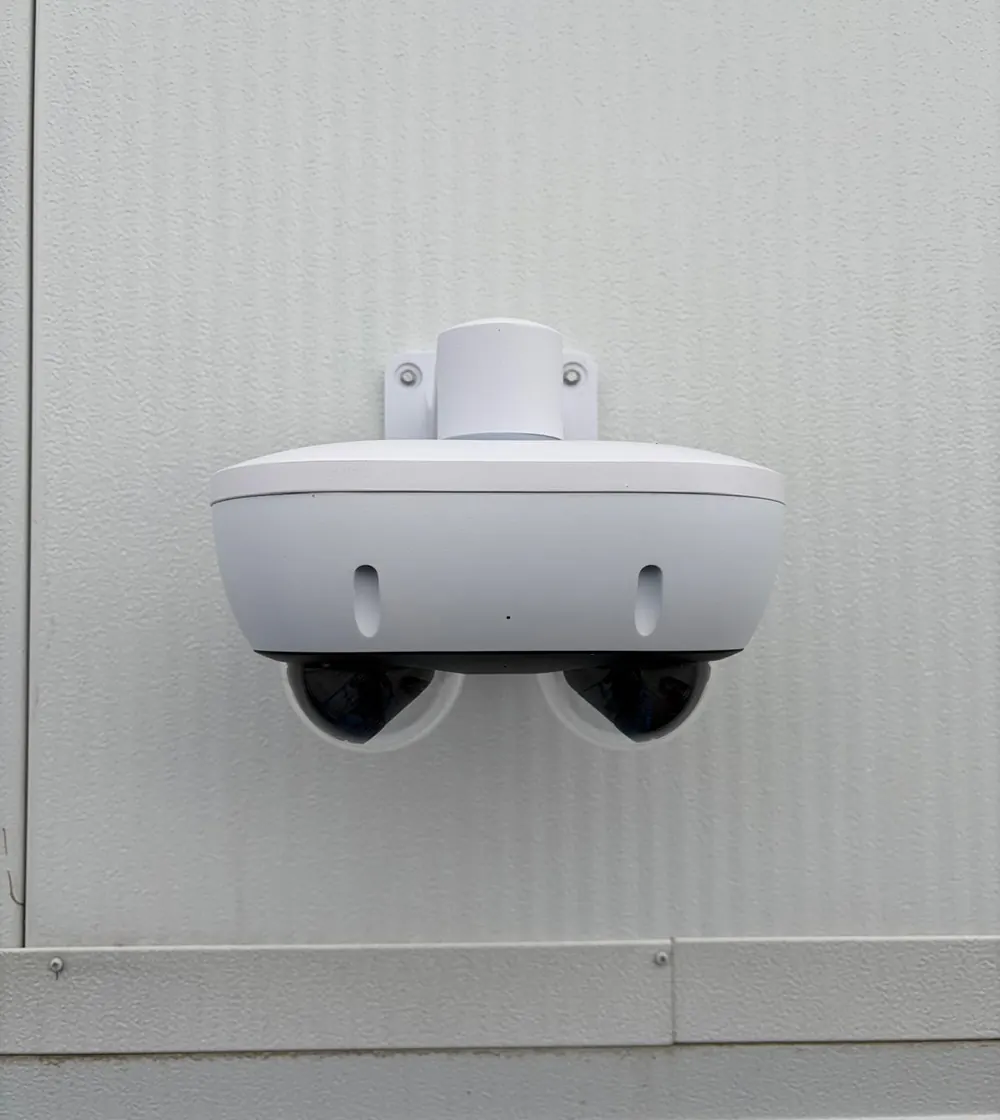 Dual-lens exterior camera mounted on a white wall