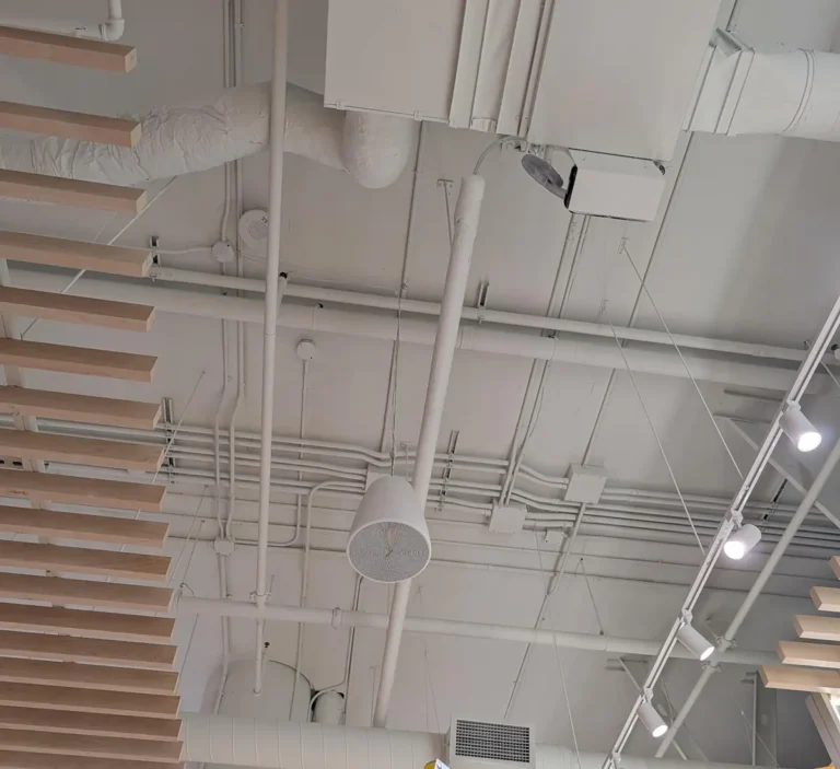 White pendant speaker hanging from an exposed ceiling