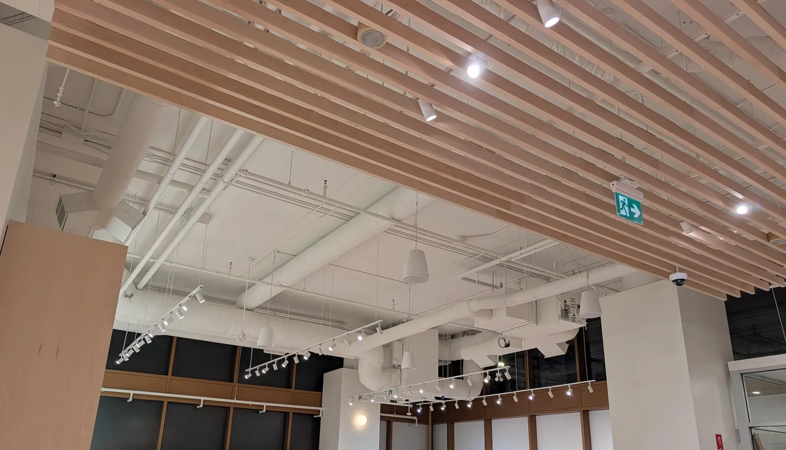 Pendant speakers and a dome camera under a wood-slat ceiling